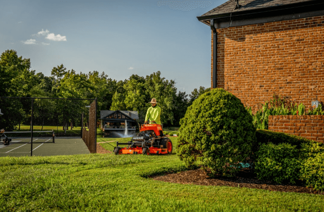 Kubota SZ26 stand-on mower trimming around landscaping, for sale at Bobby Ford in Angleton